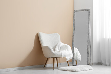 Floor mirror and armchair near beige wall in interior of room