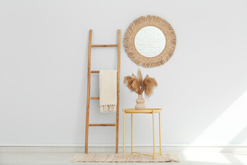 Stepladder, table and mirror on white wall in interior of room