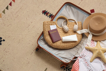 Packed suitcase with starfish and beach accessories on carpet in room, closeup