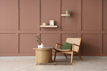 Wooden table and wicker armchair near brown wall in interior of room