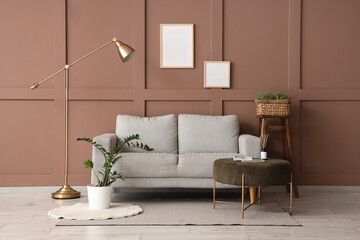 Sofa, pouf and floor lamp near brown wall in interior of room