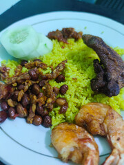 Indonesian yellow rice with fried chicken, shrimp, peanuts, sambal, and cucumber. Traditional...