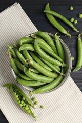 Fresh ripe green peas on black wooden table, flat lay