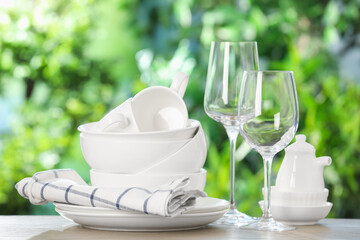 Different clean dishes on wooden table against blurred green background
