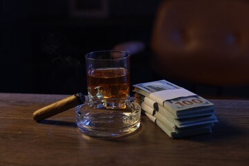 Ashtray with cigar, money and whiskey on wooden table in mafia boss office