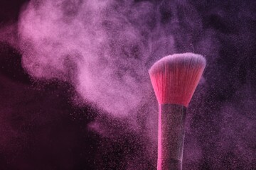 Makeup brush with pink eye shadow on black background, closeup