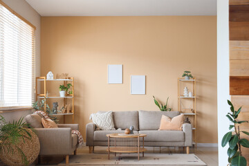 Interior of living room with houseplants and sofas near beige wall, closeup