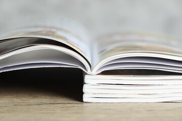 Stack of different magazines on wooden table, closeup