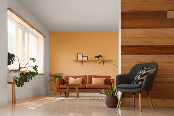 Leather brown sofa, table and armchair in interior of stylish living room