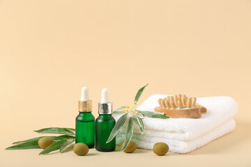 Bottles of essential olive oil, towels and massage body brush on beige background