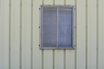 Cage on window. Yellow metal building.