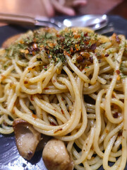 Close-up of spicy spaghetti pasta with mushrooms, herbs, and chili flakes on plate. Delicious close-up shot of spicy spaghetti pasta topped with herbs, chili flakes, and savory mushrooms.