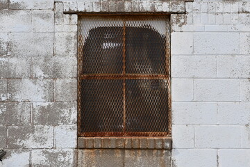 Rusty caged window on old brick building.