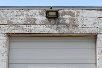 Floodlight above garage door on old brick building.