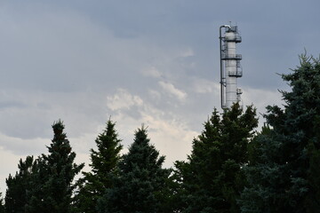 Oil refinery smokestack in background of beautiful park.