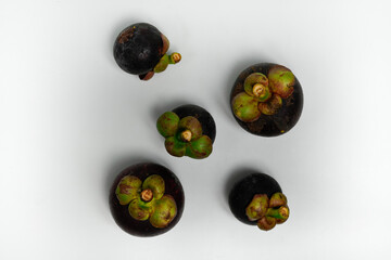 A vibrant collection of ripe raw mangosteen fruits arranged on a white background.
