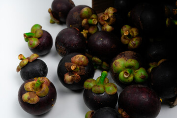 A vibrant collection of ripe raw mangosteen fruits arranged on a white background.
