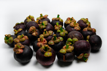 A vibrant collection of ripe raw mangosteen fruits arranged on a white background.
