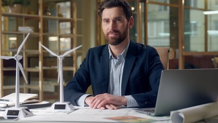Happy Caucasian business man engineer windmill model working laptop showing thumb up gesture at...