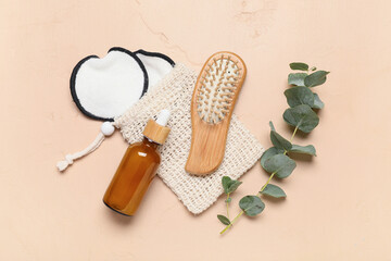 Composition with bag, hair brush, green twig and bottle of cosmetic product on beige background