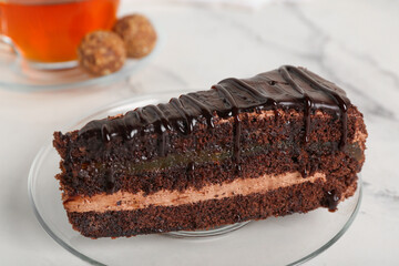 Plate with piece of tasty chocolate cake on marble background, closeup