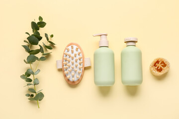 Composition with bottles of cosmetic products, green twig and massage body brush on beige background