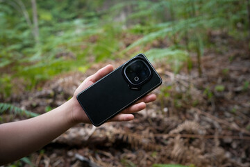 close-up of smartphone held outdoors in natural wilderness