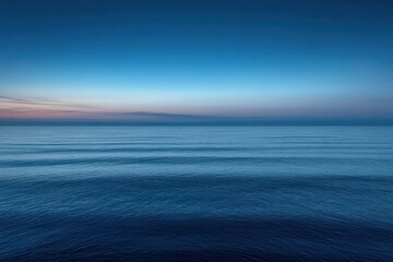 Obraz premium Calm ocean surface at dusk with gentle ripples under a clear gradient sky transitioning from soft purple near the horizon to deep blue overhead
