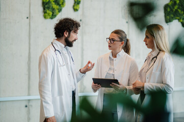 Doctors discussing patient data using tablet in hospital corridor