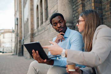 Business colleagues discussing work on tablet outdoors