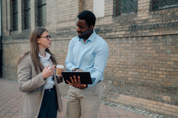 Business colleagues discussing work on tablet outdoors