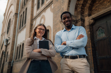 Business people smiling outside institutional building holding tablet