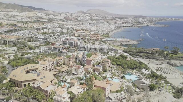 Drone orbits to the right over Playa del Duque beach on sunny day in Costa Adeje, Tenerife, Canary Islands, Spain