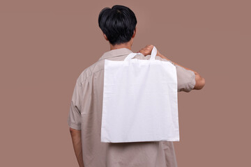 Back View of Man Hold Canvas Tote Bag with Blank Space for Design Mock-Up