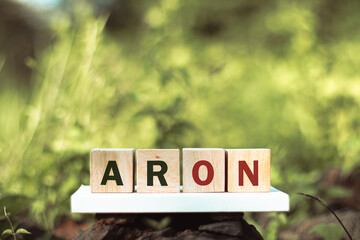 Wooden blocks spell out the word 'ARON', with the letters 'AR' in black and 'ON' in red, set...