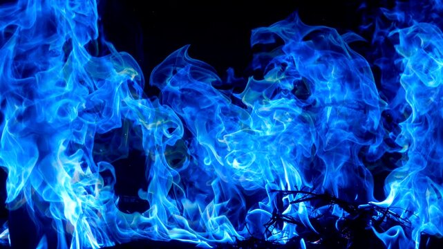Captivating blue flame: Swirling blue flame dancing across dark, A mesmerizing display of energy and movement