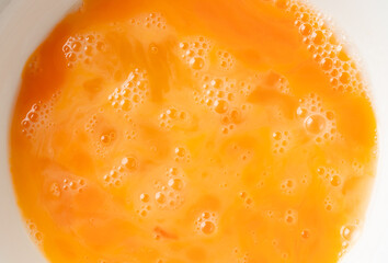 Close-up of beaten egg yolks with bubbles. Top view shot