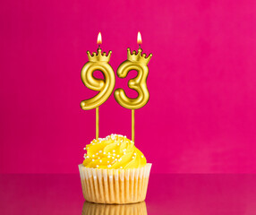 Birthday celebration with number 93 candle - Yellow cupcake on a pink background
