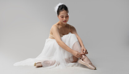Young ballerina tying ribbons on point shoes A moment of focus and preparation before the dance