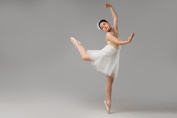 Ballerina in graceful pose light beige leotard white tutu feather in hair pointe shoes