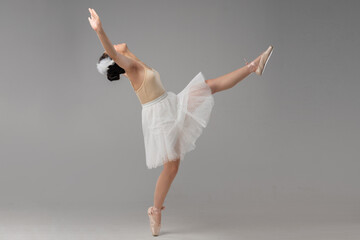 Elegant ballerina in motion gracefully posing with poise and precision on a neutral background