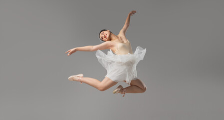 Fototapeta premium Graceful ballerina leaps mid-air in elegant dance pose a symbol of artistry and dedication