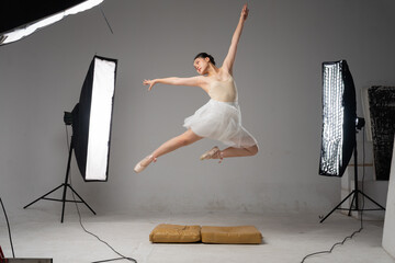 A dancer jumps during a ballet performance in a studio She is wearing a leotard and tutu