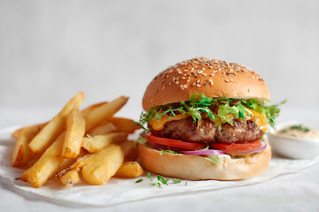 Juicy Cheeseburger with Lettuce, Tomato, and French Fries on White Parchment