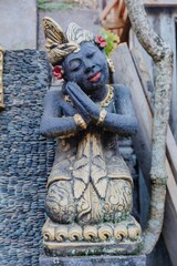 A Balinese statue of a woman in prayer, adorned with gold accents, stands serenely in Bali. The...