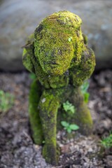 Moss-covered statue in a garden in Ubud, Bali, Indonesia. The statue is a depiction of a human...
