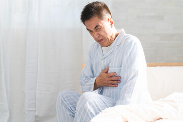 起きてベッドの上で胸を押さえている男性