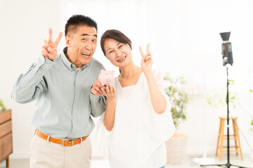 豚の貯金箱を持つ熟年夫婦