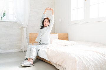 起きてベッドの上で伸びをする女性