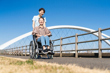 車椅子を押して散策する女性と介護士